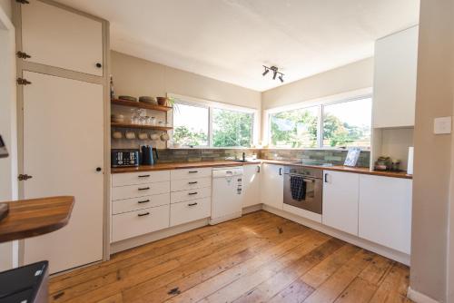 a kitchen with white cabinets and wooden floors at The Ocean Villa - Private Sauna in New Plymouth