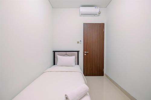 a white bed in a room with a wooden door at Elegant and Comfy 3BR Transpark Cibubur Apartment By Travelio in Depok