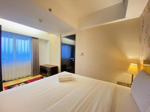 a bedroom with a large white bed and a window at Fancy and Nice 2BR at Braga City Walk Apartment By Travelio in Bandung