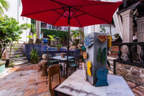 a patio with a table with a red umbrella at Garlands Del Rio Riverside Boutique Hotel in Puerto Vallarta