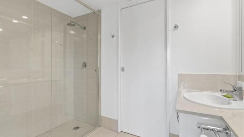 a white bathroom with a shower and a sink at Coral Sands Beachfront Resort in Trinity Beach