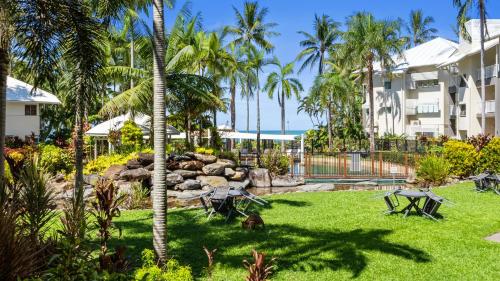 a yard with palm trees and a building at Coral Sands Beachfront Resort in Trinity Beach