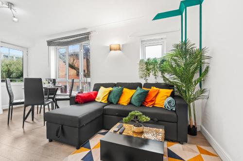 a living room with a black couch with colorful pillows at Modern 2BR Apartment Near Canary Wharf Ideal for Business 02 Arena in London
