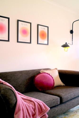 a living room with a couch with a pink pillow at Tranquility in the Meadows - 20 minutes to the City - 6 mins to the beach in Altona Meadows