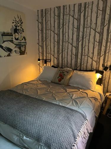 a bedroom with a bed with trees on the wall at Apple Tree Lane Cottage in Bowral
