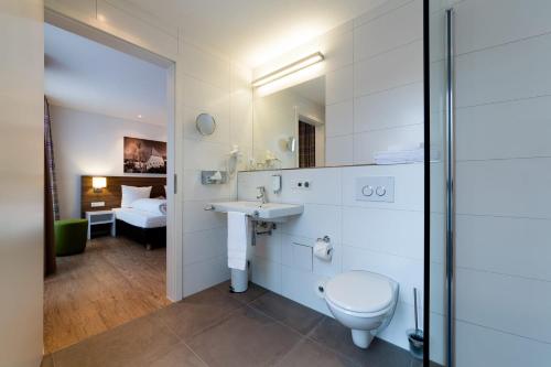 a bathroom with a sink and a toilet and a bedroom at SCHLAFGUT Domhof erleben in Guntersblum