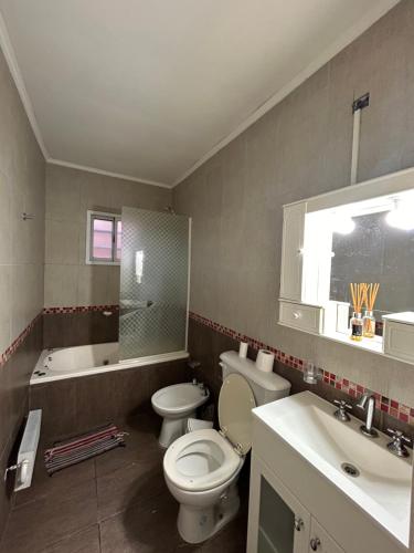 Un baño con inodoro, lavabo y bañera. en Casa de barrio, en Monte Hermoso
