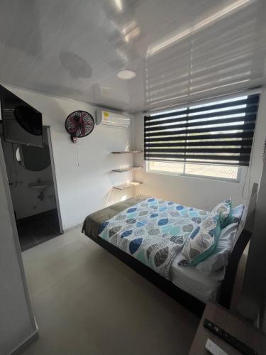 1 dormitorio con 1 cama y ventana con reloj en KlanDestino Hotel, en Santa Marta