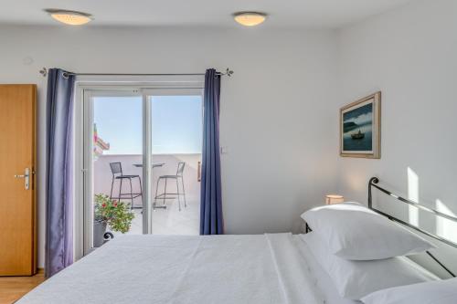 a bedroom with a bed and a balcony with a table at Pink Inn in Podstrana