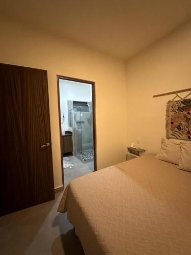 a bedroom with a bed and a door to a shower at Condo Mezcales in Mezcales