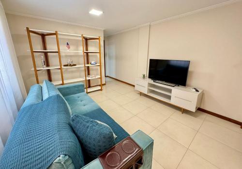 a living room with a blue couch and a tv at Conforto e Praticidade no Centro de Friburgo! in Nova Friburgo