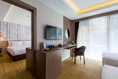 a hotel room with a bed and a desk and a television at GLOW Ao Nang Krabi in Ao Nang Beach
