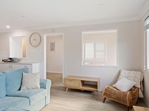 Marg's - Oceanstays - Oceanfront في Brooms Head: غرفة معيشة مع أريكة زرقاء وكرسي