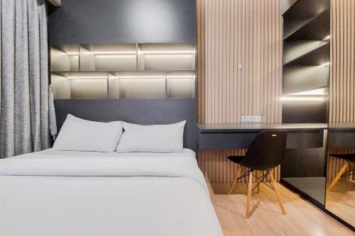 a bedroom with a bed and a desk and a chair at Well Furnished and Cozy 2BR Sky House BSD Apartment By Travelio in Tangerang