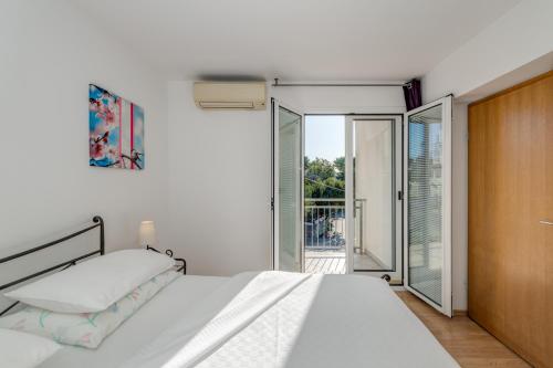 a white bedroom with a bed and a sliding glass door at Pink Inn in Podstrana
