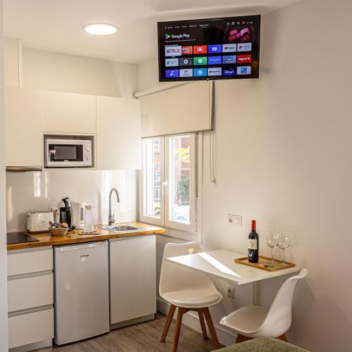 a kitchen with white cabinets and a table with chairs at Bambú Suites Vegueta Alquiler por Habitación in Las Palmas de Gran Canaria