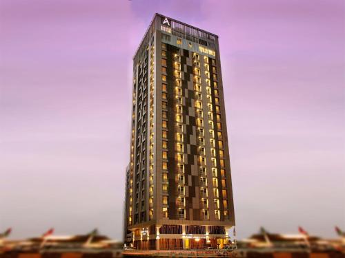 a tall building with lights on the side of it at Hala Arjaan by Rotana, Deluxe Hotel Apartments in Abu Dhabi
