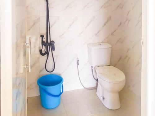 a bathroom with a toilet and a blue bucket at RedDoorz Syariah near Pengadilan Agama Wonosobo in Wonosobo