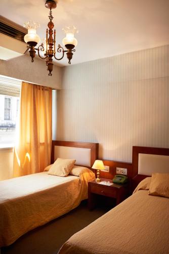 a bedroom with two beds and a chandelier at Blanro Hotel in Buenos Aires