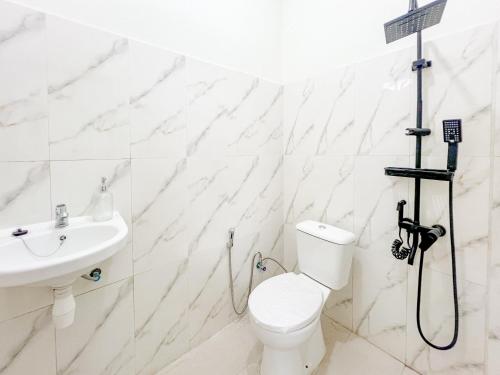 a white bathroom with a toilet and a sink at RedDoorz Syariah near Pengadilan Agama Wonosobo in Wonosobo