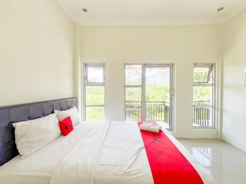 a bedroom with a white bed with a red stripe on it at RedDoorz Syariah near Pengadilan Agama Wonosobo in Wonosobo