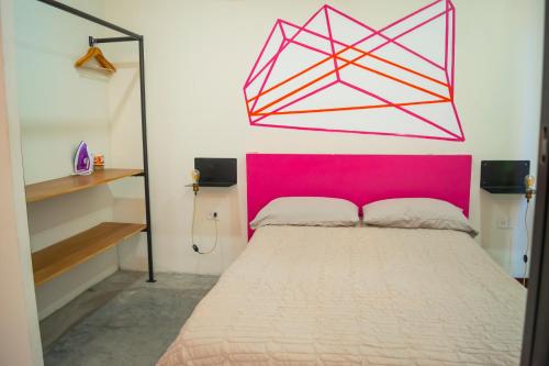 a bed with a pink headboard in a room at Loft a 3 cuadras de la playa by G P S rentas in Mazatlán
