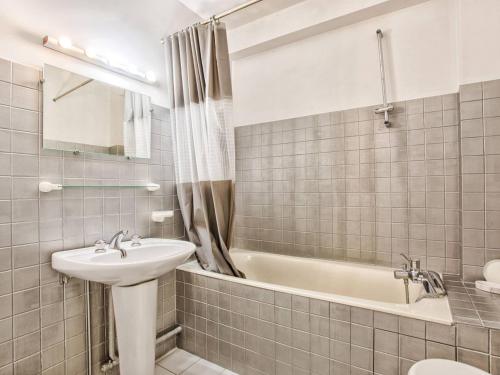 une salle de bain avec un lavabo et une baignoire dans l'établissement Appartement en duplex avec piscine chauffée, idéal pour 6 personnes - FR-1-788-61, à Varaville