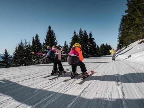 Deux enfants sont en train de skier sur une piste enneigée. dans l'établissement Studio confortable pour 3 pers. à Châtel avec parking - FR-1-676-214, à Châtel