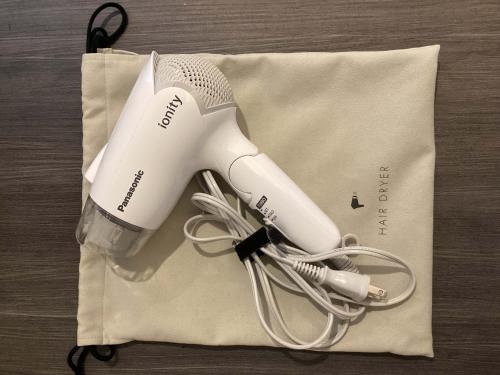 a white hair dryer sitting on top of a bag at Prince Smart Inn Miyazaki in Miyazaki