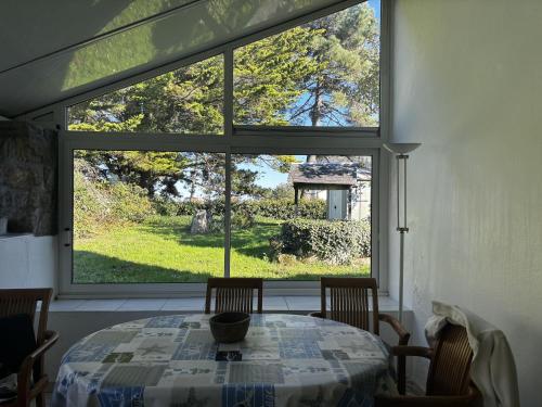 une table et des chaises dans une pièce avec une grande fenêtre dans l'établissement Maison 3P Proche Vieux Passage, Animaux Acceptés - FR-1-397-82, à Plouhinec