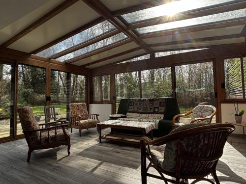 une véranda avec un canapé et des chaises dans l'établissement Maison spacieuse près de la forêt avec 3 ch. et WIFI - Nostang - FR-1-397-84, à Nostang