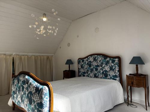 une chambre avec un lit et un lustre dans l'établissement Maison spacieuse près de la forêt avec 3 ch. et WIFI - Nostang - FR-1-397-84, à Nostang