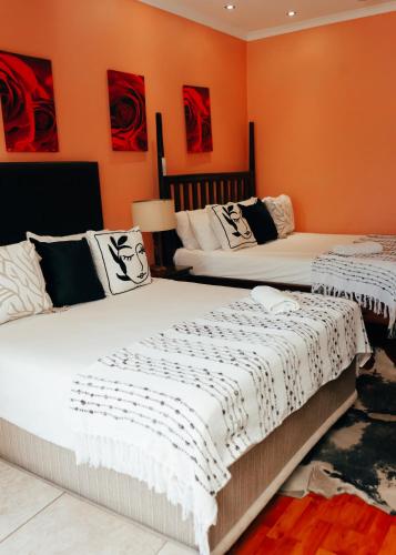 two beds in a room with orange walls at Letona Guesthouse in Kuruman