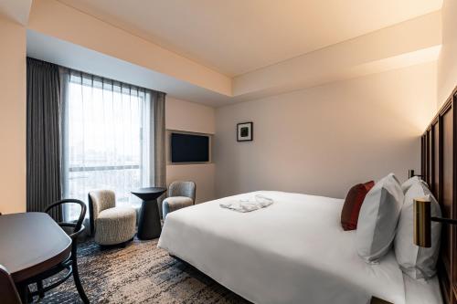 a hotel room with a bed and a table and chairs at The Gate Hotel Yokohama by Hulic in Yokohama