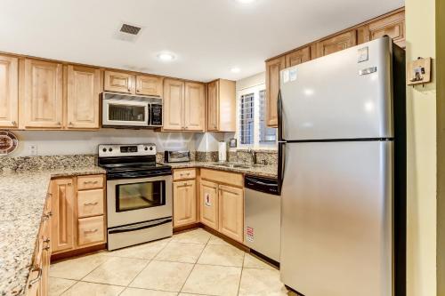 a kitchen with wooden cabinets and a stainless steel refrigerator at Fresh Oceanfront Condo in Fernandina Beach