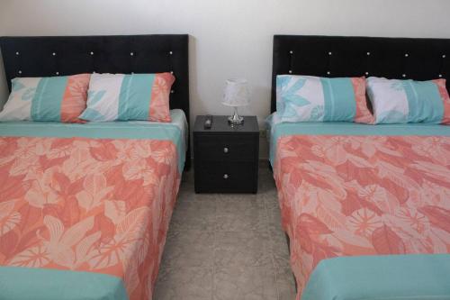a bedroom with two beds and a night stand at Apartamento con buena ubicación PARA FAMILIA Grande in Cali
