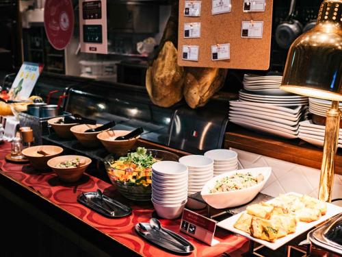 a buffet with plates and bowls of food on a table at Hotel Resol Trinity Kanazawa in Kanazawa