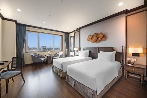 a hotel room with two beds and a table and chairs at Ninh Binh Legend Hotel in Ninh Binh