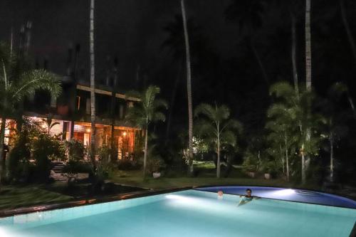 a person in a swimming pool at night at Hotel Riverrina in Negombo