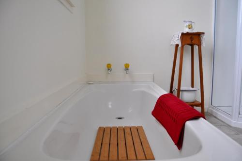 a bath tub with a wooden bench in a room at Shunters Cottage in Waihi