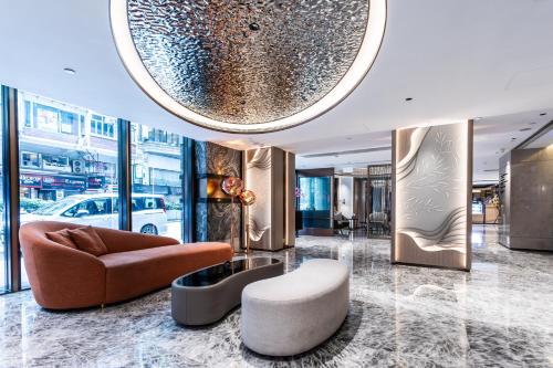 a lobby with a couch and a chair and a stool at Wharney Hotel in Hong Kong
