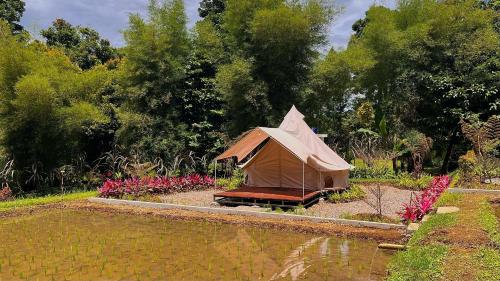 a tent sitting next to a body of water at Bamboo Sanctuary Pancawati Resort Bogor in Ciherangsating