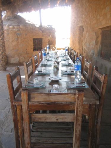 a long wooden table with chairs and bottles of water at Maison Boutchrafine in Erfoud
