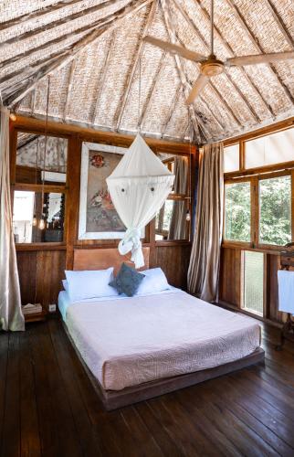 a bedroom with a bed in a straw roof at BoHo Bingin Beach Bali in Uluwatu