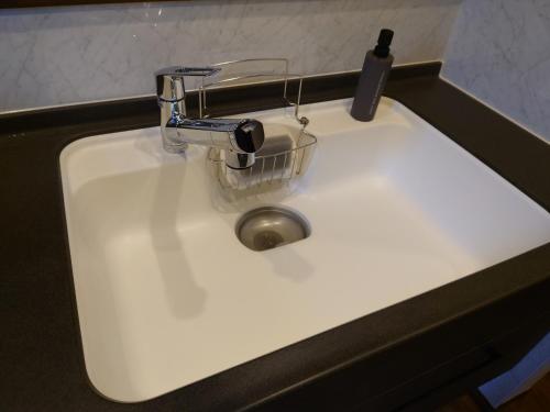 a white sink with a faucet and a basket on it at 川越の家夜風 小江戸観光に最適 川越市駅5分 庭付き新築一軒家 Bbq可 最大12名 駐車場2台小型車のみ in Kawagoe