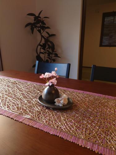 a black vase with pink flowers on a table at 川越の家夜風 小江戸観光に最適 川越市駅5分 庭付き新築一軒家 Bbq可 最大12名 駐車場2台小型車のみ in Kawagoe