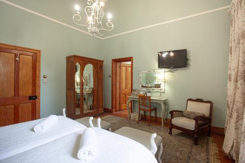 a bedroom with two beds and a desk and a mirror at Sundays Karoo Guesthouse in Graaff-Reinet