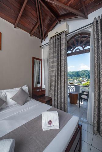 a bedroom with a bed and a large window at Ceyloni Lake Residency in Kandy