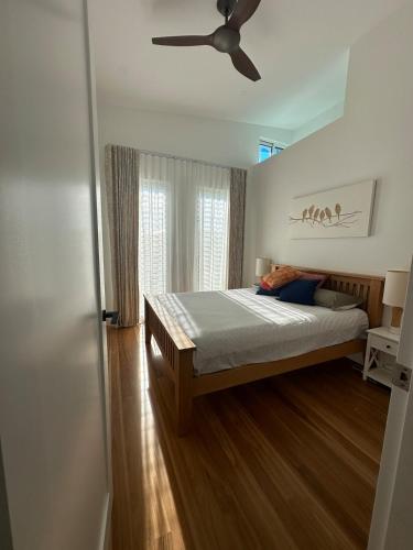 a bedroom with a bed and a ceiling fan at Plumeria Cottage Private Coastal Retreat by Australia No 1 Beach in Rock Islet