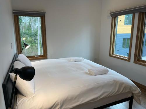 a white bed in a room with two windows at Hakobune Niseko - 8-room Chalets & 2-room Apartments in Niseko